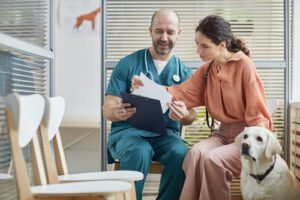 female-pet-owner-with-yellow-lab-talking-over-paperwork-with-male-vet