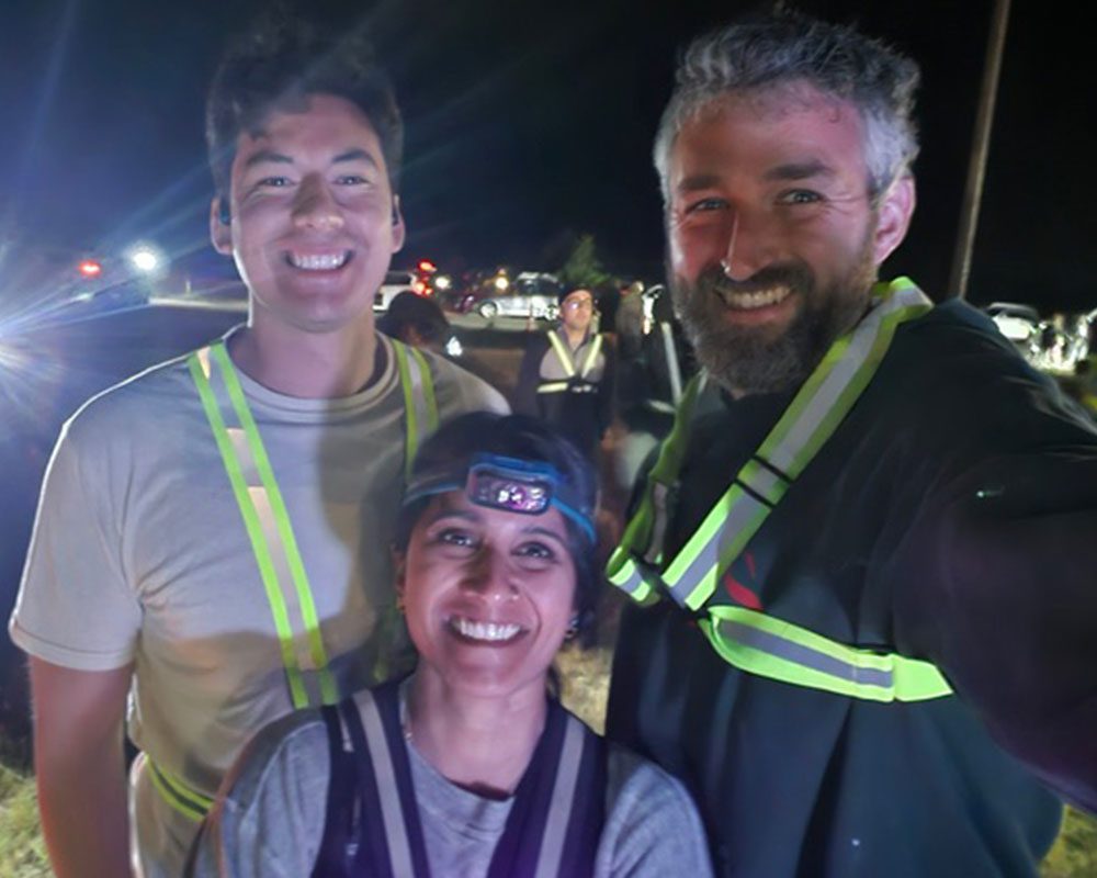 two male veterinarians and female veterinarian smiling and posing at evening event outdoors