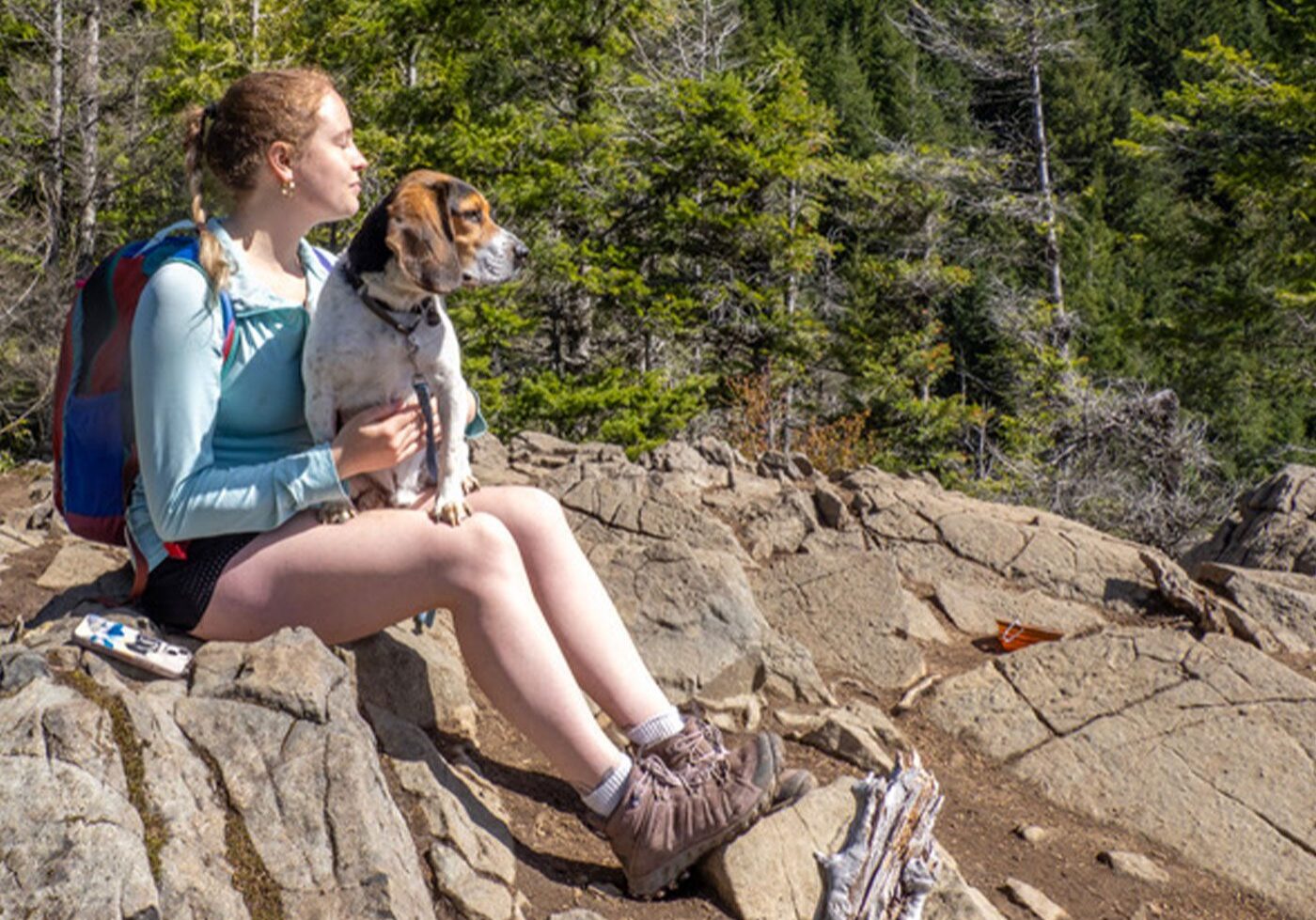 woman sitting with dog while hiking in mountains